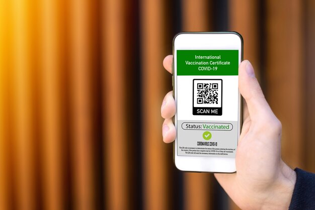 Mano maschile che tiene uno smartphone con codice QR del certificato di vaccinazione internazionale COVID-19
