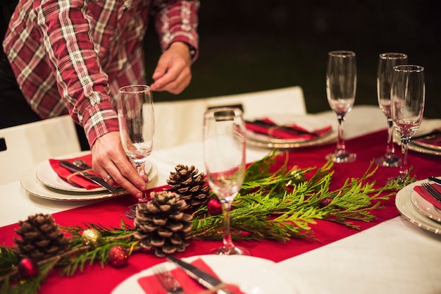 Mano ponendo il bicchiere di champagne sulla tavola di Natale