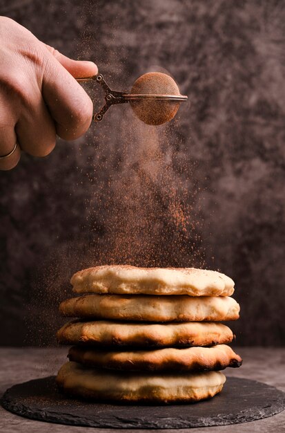 Mano setacciare il cacao in polvere sopra i pancake impilati