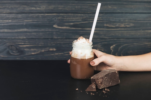 Mano sosteniendo cioccolata calda con panna