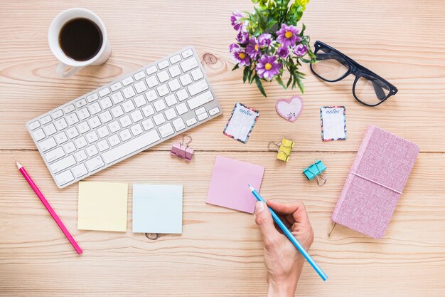 Mano sul desktop carino con tastiera caffè e stazionario