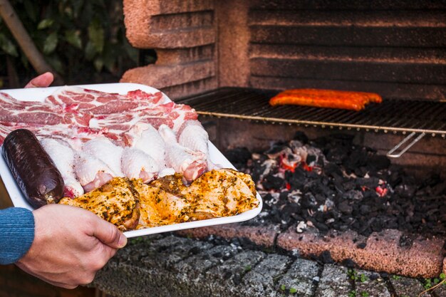 Mano umana che tiene il vassoio di carne cruda