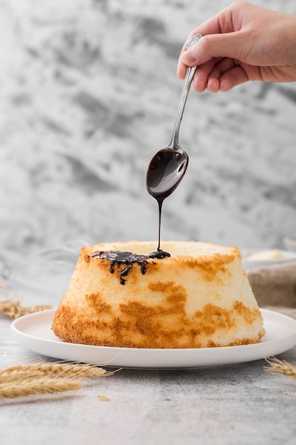 Mano versando il cioccolato sulla torta fatta in casa