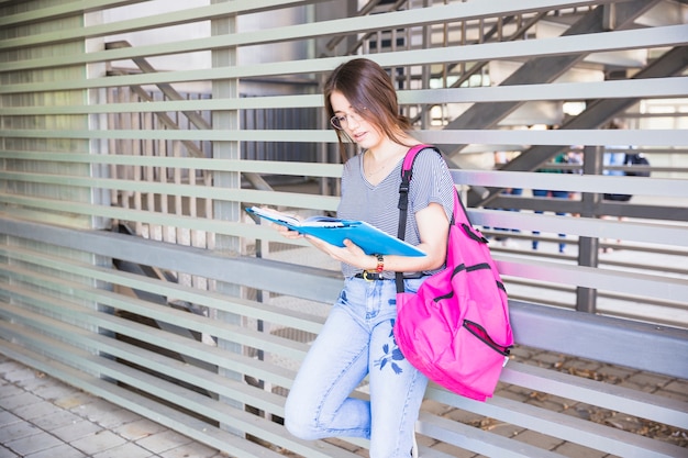 Manuale della lettura della studentessa vicino alla parete