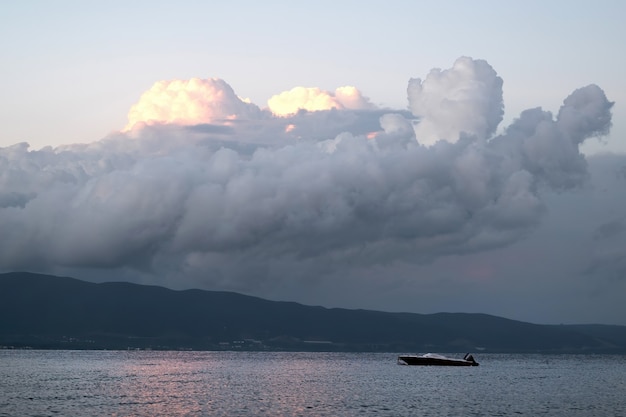 Mar Egeo con una barca, nuvole lussureggianti illuminate dal tramonto, Grecia