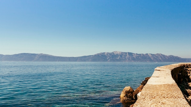 Mare calmo e idilliaco con montagna e cielo blu chiaro