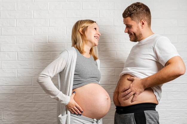 Marito divertente che confronta la sua pancia con la moglie incinta