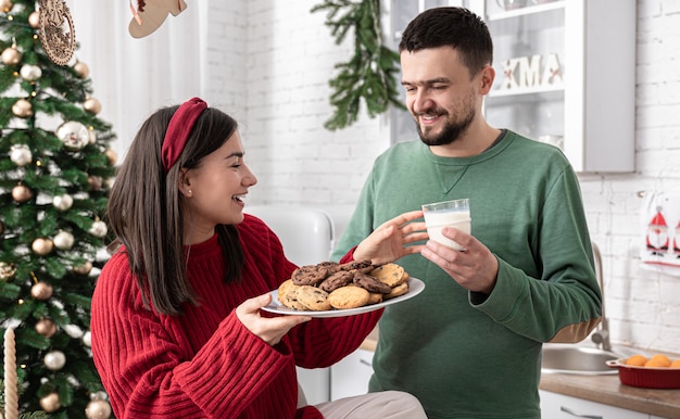 Marito e moglie felici con biscotti di Natale e latte in cucina.