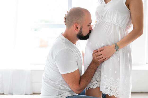 Marito laterale che bacia la pancia della moglie