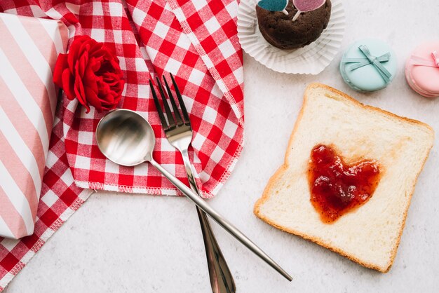 Marmellata a forma di cuore su pane tostato con forchetta e cucchiaio