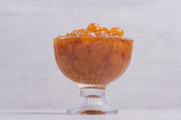 Marmellata di ciliegie in vetro sul tavolo bianco.