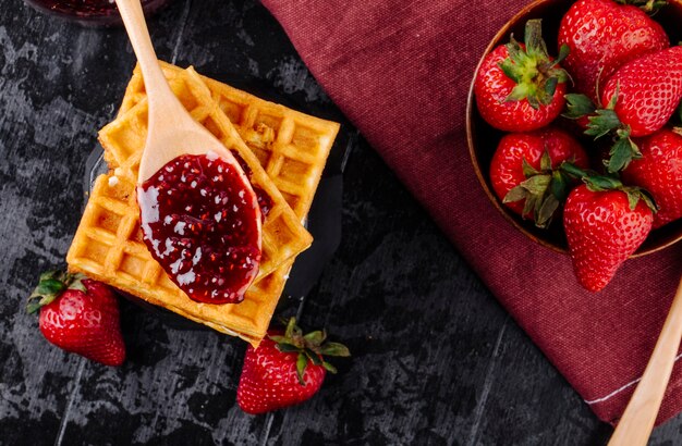 Marmellata di fragole vista dall'alto e cialde su sfondo nero