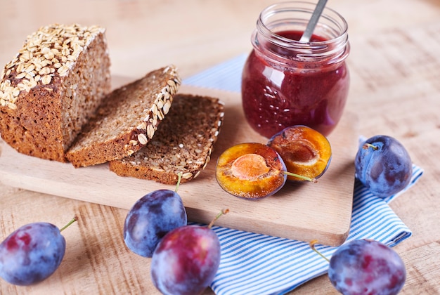 Marmellata di prugne fatta in casa con pane fresco sul tagliere