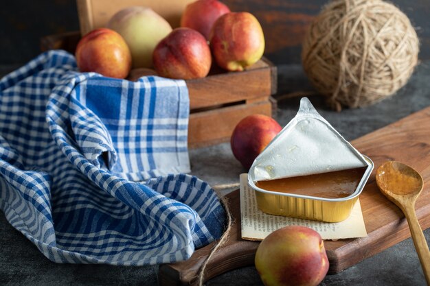 Marmellata dolce con pesche e cucchiaio di legno su tavola di legno