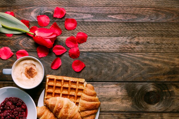 Marmellata in una ciotola, fiori freschi, prodotti da forno, petali e tazza di bevanda