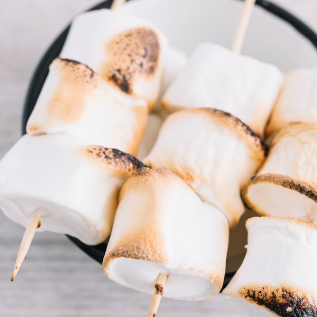 Marshmallow arrostiti su bastoncini sulla tazza