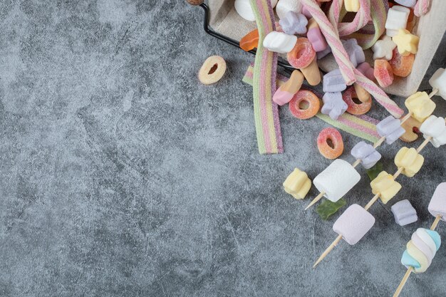 Marshmallow colorati sui bastoncini di legno per grigliare.