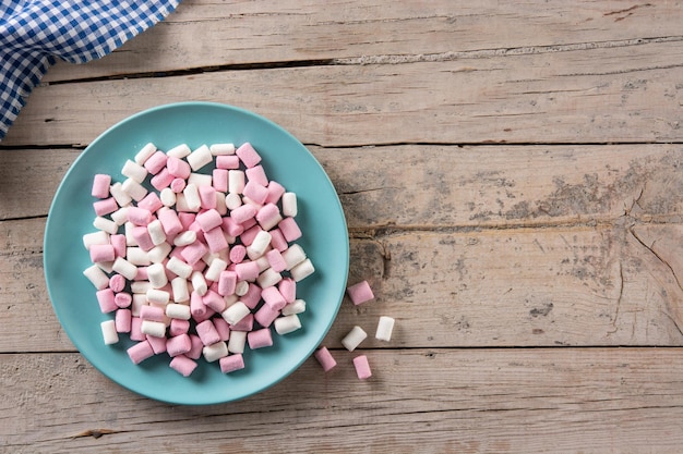 Marshmallow dolci che topping in un piatto blu su un tavolo di legno