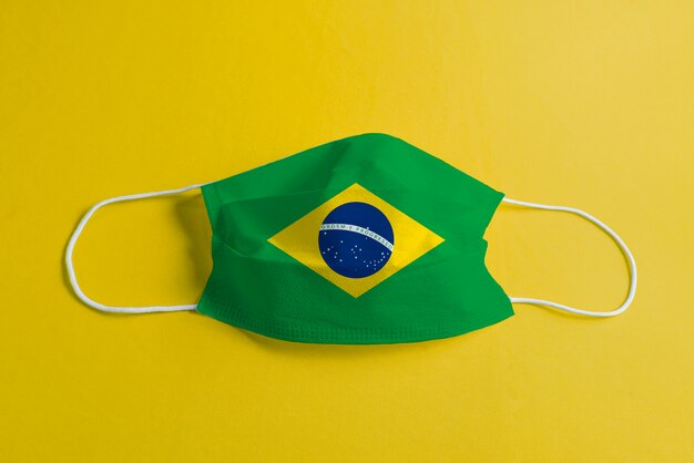 Maschera chirurgica su sfondo giallo con bandiera brasiliana