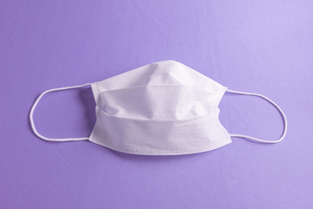 Maschera chirurgica su sfondo viola minimalista