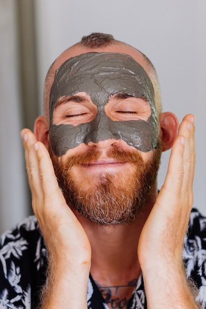 maschera di argilla sul viso giovane uomo bello in clinica di bellezza