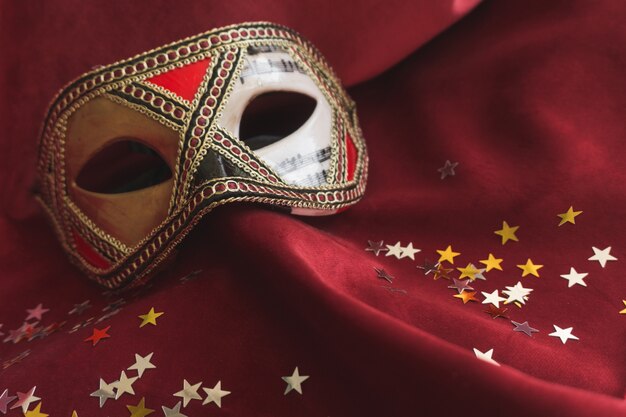 Maschera veneziana su un tessuto rosso con coriandoli stella