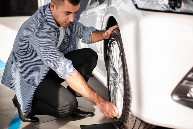 Maschio adulto che controlla le gomme di automobile