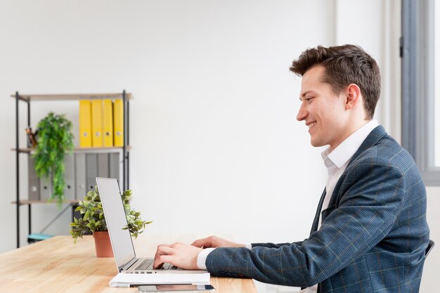 Maschio adulto di vista laterale che lavora al computer portatile