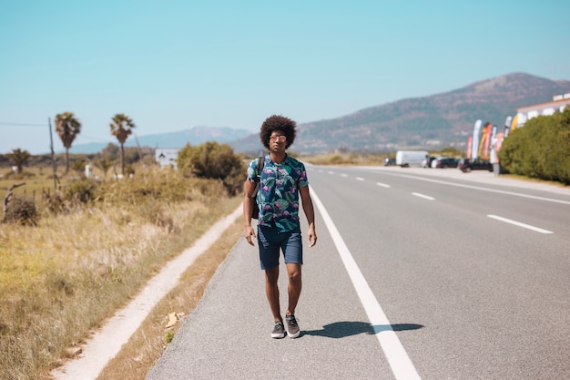 Maschio afroamericano che cammina sul bordo della strada