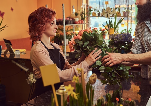 Maschio barbuto acquisto bouquet di fiori in un negozio di fiori.