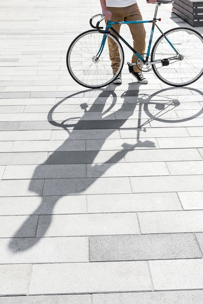 Maschio casuale che controlla la sua bicicletta all'aperto