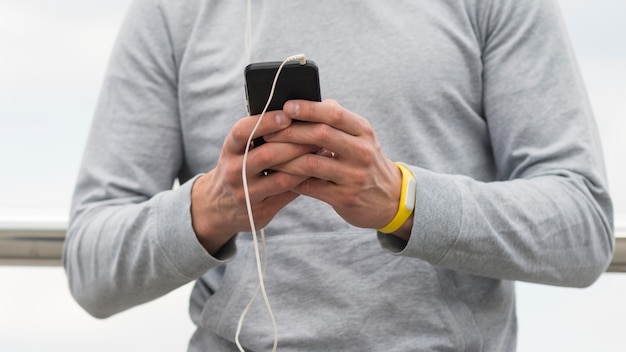 Maschio del primo piano che passa in rassegna il suo telefono cellulare