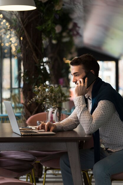 Maschio di affari di vista laterale che parla al telefono