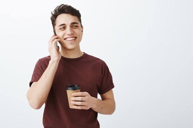 maschio di bell'aspetto felice in maglietta rossa parlando per telefono