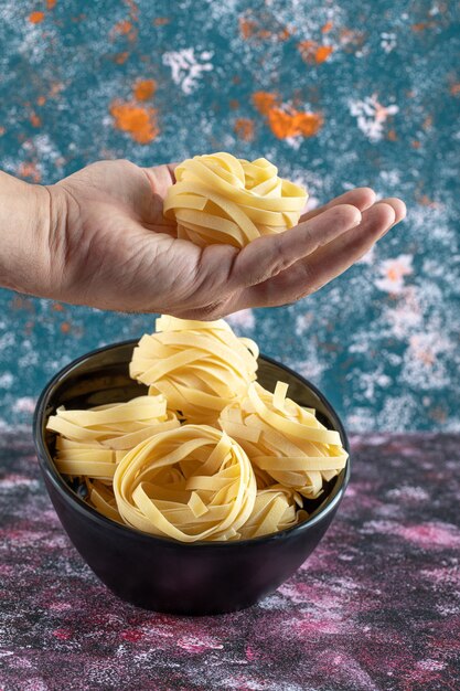 Maschio di mano azienda nido di tagliatelle su sfondo colorato. Foto di alta qualità