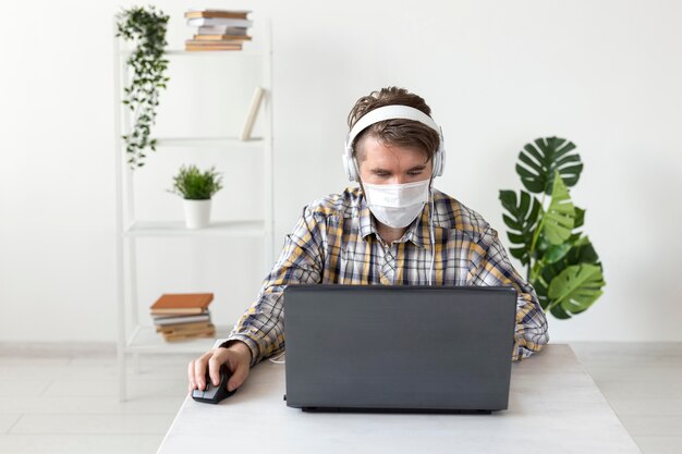 Maschio di vista frontale con maschera facciale che lavora da casa