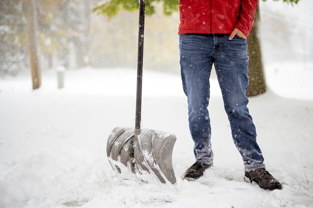 Maschio in piedi su un campo nevoso e in possesso di una pala da neve