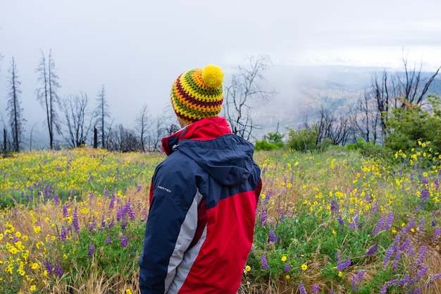 Maschio in un cappotto in piedi in un bellissimo campo di fiori