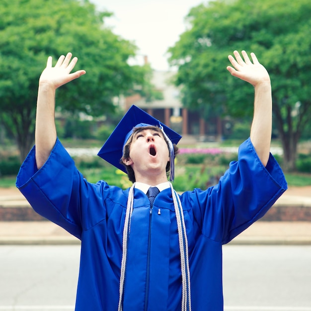 Maschio in un manto blu che gode della libertà dopo la laurea