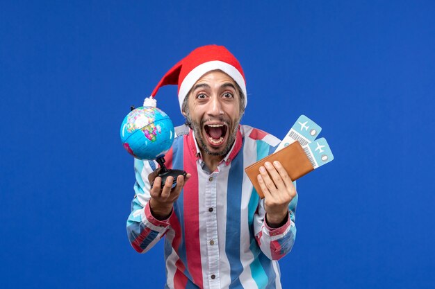 Maschio regolare di vista frontale con globo e biglietti sul muro blu emozioni vacanza capodanno