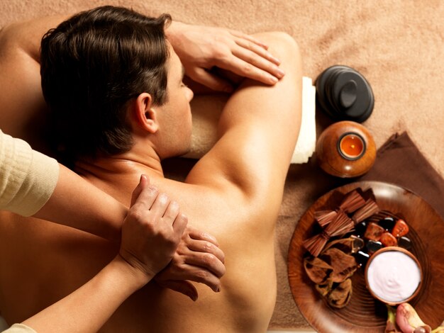 Massaggiatore che fa massaggio della spina dorsale sul corpo dell'uomo nel salone della stazione termale. Concetto di trattamento di bellezza.