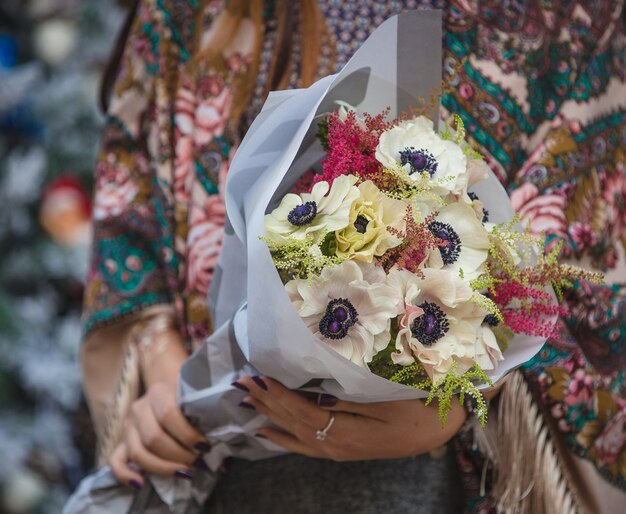 Mazzo bianco dei windflowers nelle mani di una donna in scialle di soho