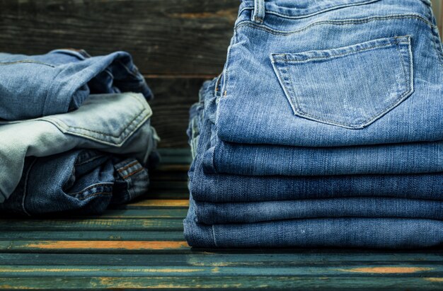 mazzo di jeans sulla parete in legno, vestiti alla moda