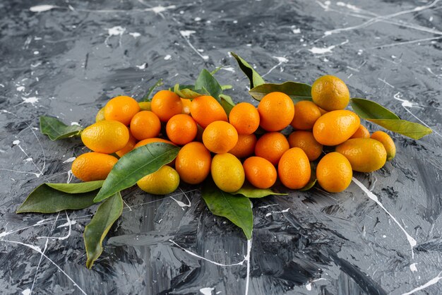 Mazzo di kumquat maturi con foglie verdi sulla superficie in marmo.