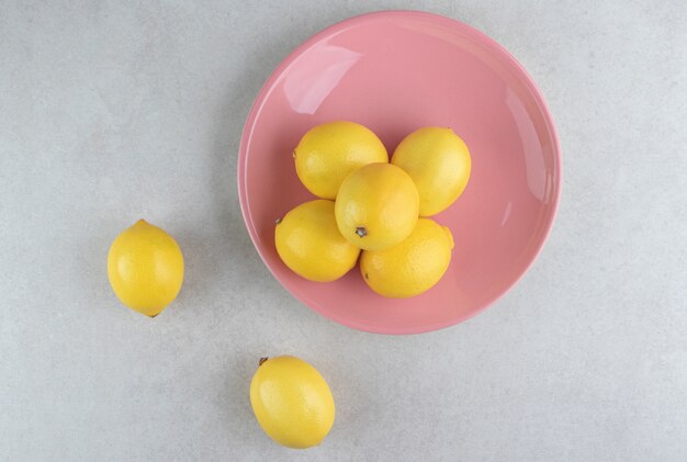 Mazzo di limoni gialli sulla zolla rosa.