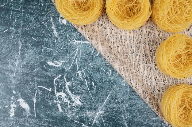 Mazzo di nidi di spaghetti crudi su tela. Foto di alta qualità