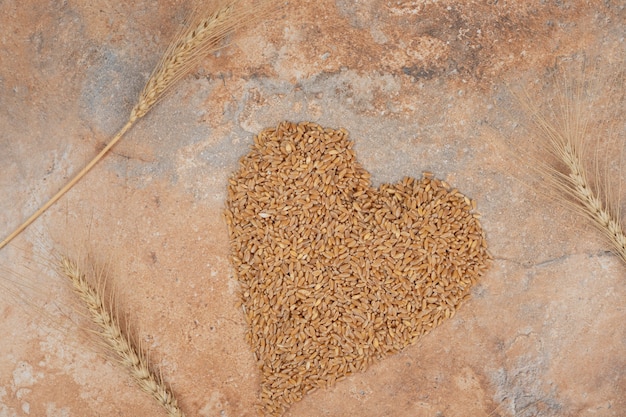 Mazzo di orzo formato come cuore su sfondo arancione