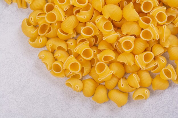 Mazzo di pasta cruda a forma di conchiglia sulla superficie bianca