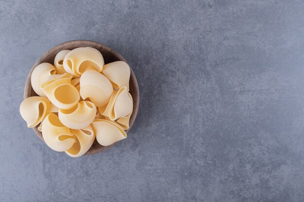 Mazzo di pasta cruda delle coperture in ciotola di legno.