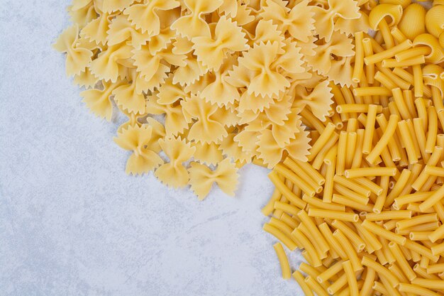 Mazzo di pasta grezza a spirale e farfalle sulla superficie di pietra